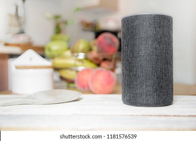 Personal assistant connected loudspeaker on a wooden table in a Smart Home in a kitchen. Next, some utensils, food and fruit. Empty copy space for Editor's text.