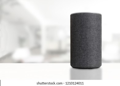 Personal assistant loudspeaker on a white wooden shelf of a smart home living room. Next, a carton box with the order, a plant and some books. Empty copy space for Editor's text.