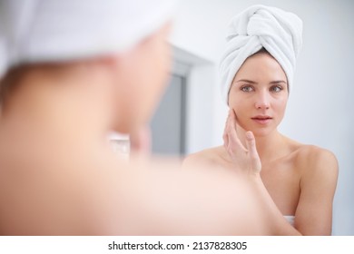 Personal Beauty Regime. A Woman Looking In Her Bathroom Mirror With A Towel On Her Head.