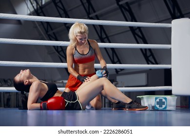 Personal coach, team trainer helping female boxer to relax, avoid injuries during the boxing training in the gym. Concept of first aid, medicine, health, safety and active lifestyle - Powered by Shutterstock