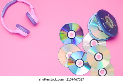 Personal compact portable CD player disks purple headphones on a pink background. Top view layout, copy space, place for text or advertising. Hobby entertainment leisure