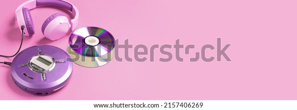 Personal compact portable CD player disks\
purple headphones on a pink\
background.