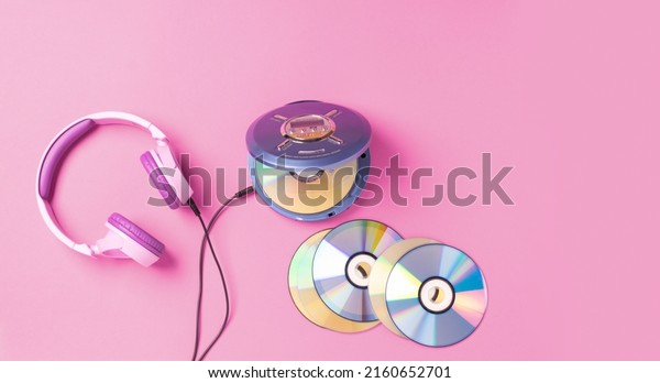 Personal compact\
portable CD player disks purple headphones on a pink background.\
Top view layout, copy space, place for text or advertising. Hobby\
entertainment leisure