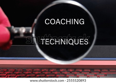 Personal development concept. COACHING TECHNIQUES words through a magnifying glass on a black background.