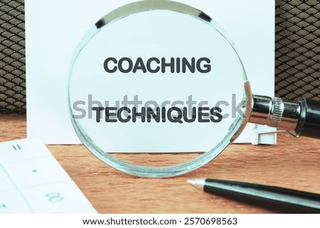 Personal development and self improvement. The concept of technology and business development. The concept phrase COACHING TECHNIQUES on a white sheet through a magnifying glass, front view.