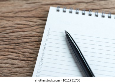 Personal to do lists or work, tasks priority concept, closed up of list of numbers on white clean paper notepad with black pen on wood table in soft tone, organize or writing projects.
