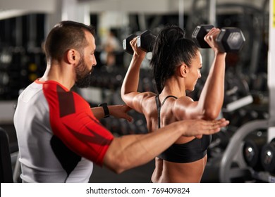 Personal Fitness Trainer Assisting A Young Woman With Workout