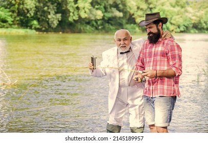 Personal instructor. Expert fisherman. Bearded man elegant businessman fish together. Learn to fish. Fishing skills. Fish with companion who help in emergency. Men friends relaxing river background