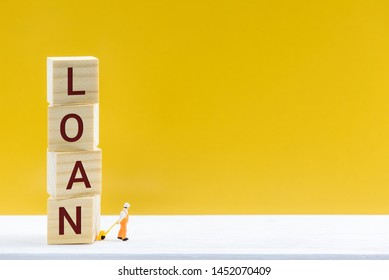 Personal loan / payday loan concept : Miniature worker uses a hand-pull pallet drags square cubes with words LOAN, depicts a sum of long-term money borrowed and expected to be paid back with interest