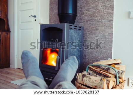 Personal perspective of person in comfortable position in front of wooden fire stove