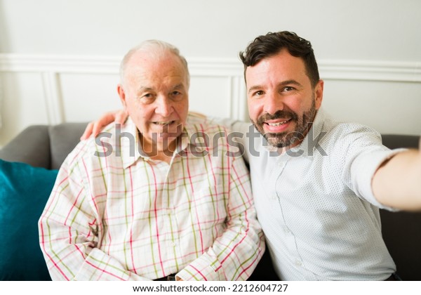 Personal
perspective of a smiling caucasian man and elderly old man taking a
selfie while spending time together at
home