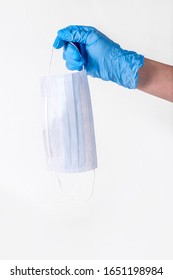 Personal Protection Against Colds And Viruses. A Medical Worker's Hand In Blue Gloves Drops A Protective Mask On A White Background. The Concept Of Maintaining Health During The Flu Season. Copy Space