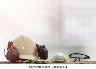 Personal Protective Equipment(PPE ) Are White Safety Helmet (hard Hat) With Ear Muff Attached,Respiratory Protection, Leather Gloves And Transparent Plastic Glasses On Old Textured Wooden Table.