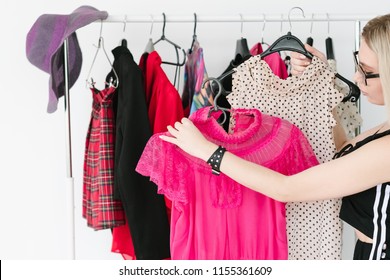 Personal Style Consultant Or Fashion Stylist Choosing Trendy Clothing For Her Client. Woman Holding Two Tops On Hangers.