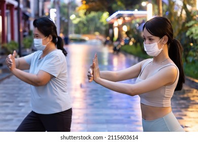 Personal Taichi Or Taijiquan Trainer With Face Mask Helping Senior Woman Doing Yoga Meditation