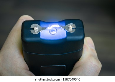 Personal Taser For Protection Against Bandits Is In The Hands. The Use Of A Stun Gun With A Powerful Electric Discharge. Turning On The Device For Self-defense. Action Of The Stun Gun Is Close-up. 