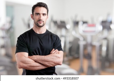 Personal trainer with is arms crossed, in a gym