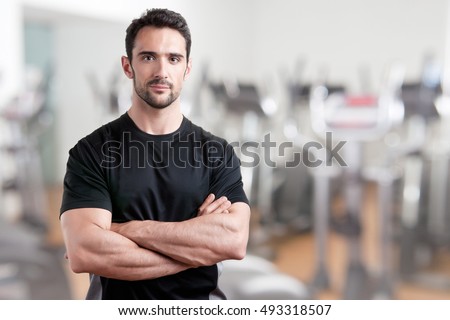 Personal trainer with is arms crossed, in a gym