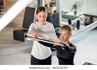 Personal trainer assisting a client with an exercise at a fitness studio