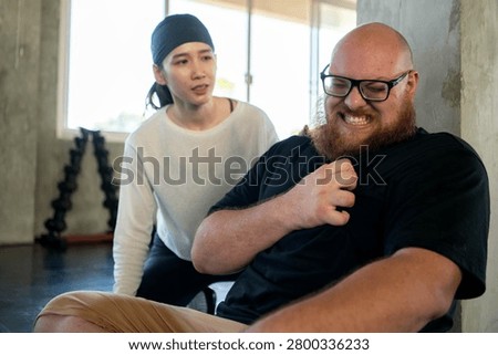 Personal trainer checking on an exhausted beginner who experienced shortness of breath and chest pain from fatigue after strenuous exercise