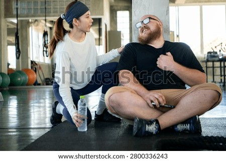 Personal trainer checking on an exhausted beginner who experienced shortness of breath and chest pain from fatigue after strenuous exercise