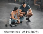 Personal trainer, coach or fitness instructor helping an active and fit woman in the gym. Young female athlete sitting down and managing her workout routine or schedule with her exercising partner