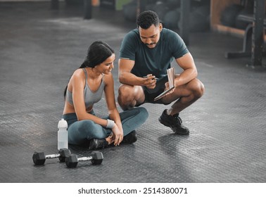 Personal trainer, coach or fitness instructor helping an active and fit woman in the gym. Young female athlete sitting down and managing her workout routine or schedule with her exercising partner - Powered by Shutterstock