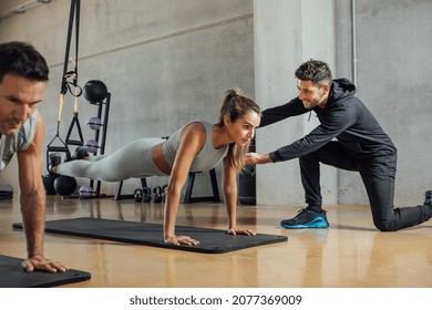 Personal trainer corrects woman's plank position at gym. - Powered by Shutterstock