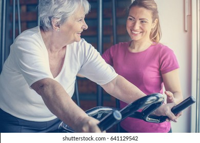 Personal trainer exercise helps senior woman. Senior woman on the elliptical machine. - Powered by Shutterstock