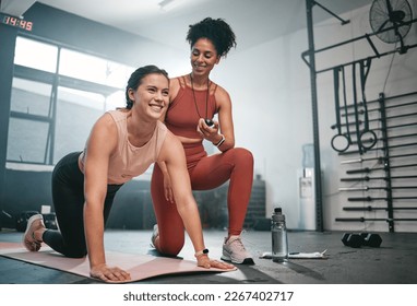 Personal trainer, exercise and stopwatch with a black woman coaching a client in a gym during her workout. Health, fitness or training and a female athlete ready to plank with a coach recording time
