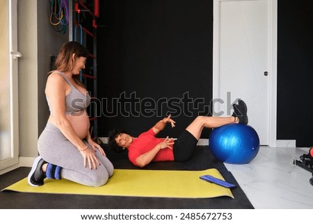 Personal trainer explaining how to do the exercise to a pregnant woman at a gym.