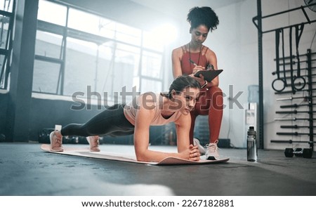 Personal trainer, fitness and clipboard with a black woman coaching a client in a gym during her workout. Health, exercise or training and a female athlete doing a plank with her coach writing notes