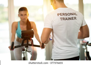 Personal Trainer At The Gym With Client On Bike 