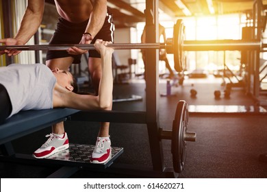 Personal trainer helping woman bench press in gym