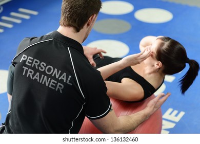 Personal trainer helping young woman in gym with crunching exercises - Powered by Shutterstock