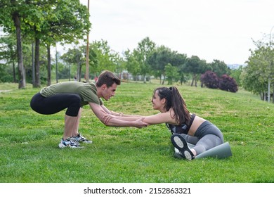 Personal Trainer Helping Young Woman Doing Splits And Stretching Exercises During Fitness Workout In A Park. Exercise Outside.