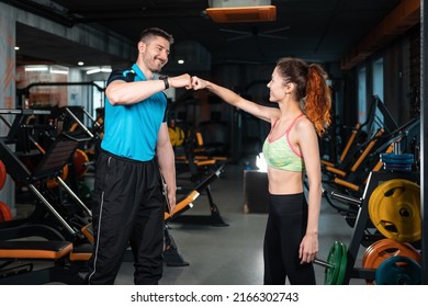 Personal Trainer High Five With Female Client After Workout In Gym