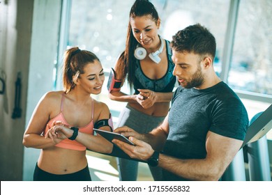 Personal trainer looking at digital tablet and explaining progress to young women at the gym - Powered by Shutterstock