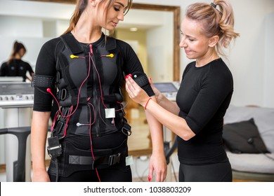 Personal trainer placing ems diodes on young woman