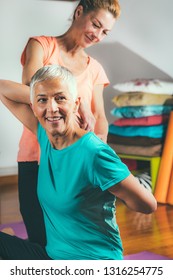 Personal trainer with senior woman practicing yoga