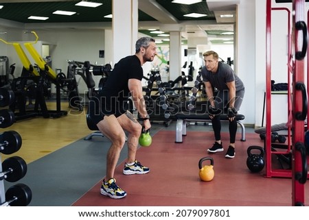 A personal trainer show to the client how correctly to lift the kettlebell in the gym. Personal workout hour with personal coach