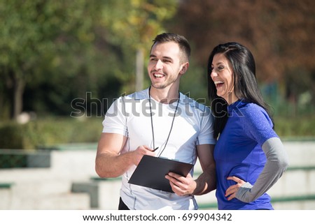 Personal Trainer Takes Notes While Young Woman Exercise in City Park Area - Training and Exercising for Endurance - Healthy Lifestyle Concept Outdoor