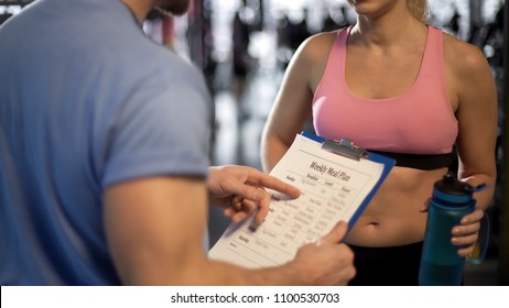 Personal trainer teaching client how to count calories, discussing meal plan - Powered by Shutterstock