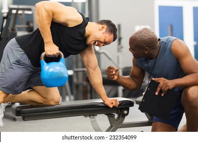 personal trainer training man with heavy kettle bell - Powered by Shutterstock