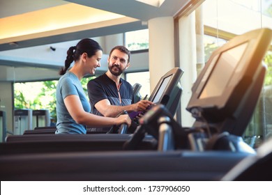 Personal trainer working with client in gym. Trainer man helping woman with her work out in treadmill - Powered by Shutterstock