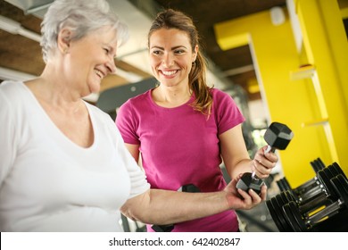 Personal trainer working exercise with senior woman in the gym. Woman picking weight. Workout in gym - Powered by Shutterstock