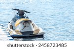 Personal watercraft tied by a rope to a modular floating plastic pontoon berth at seaside resort