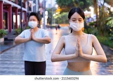 Personal Yoga Trainer With Face Mask Helping Senior Woman Doing Yoga Meditation