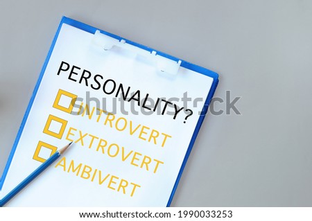 Personality introvert, extrovert and ambivert with check box on notepad with paper and pencil on grey background. Human personality type concept and shy or outgoing person idea