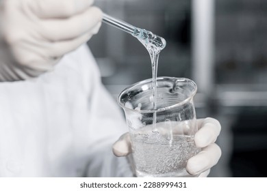 Personnel in the laboratory are mixing industrial glue, wearing gloves, professional protective clothing - Shutterstock ID 2288999431